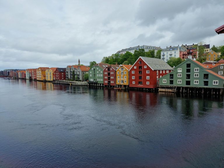 A vibrant view of colorful waterfront houses in Trondheim, Norway under overcast skies.