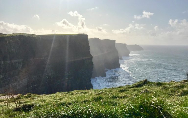 Stunning view of towering cliffs meeting the expansive ocean under a bright sky.