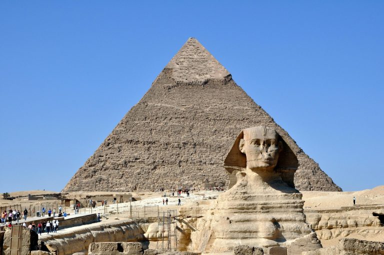 Majestic view of the Great Sphinx and Pyramid of Giza in the Egyptian desert under a clear blue sky.