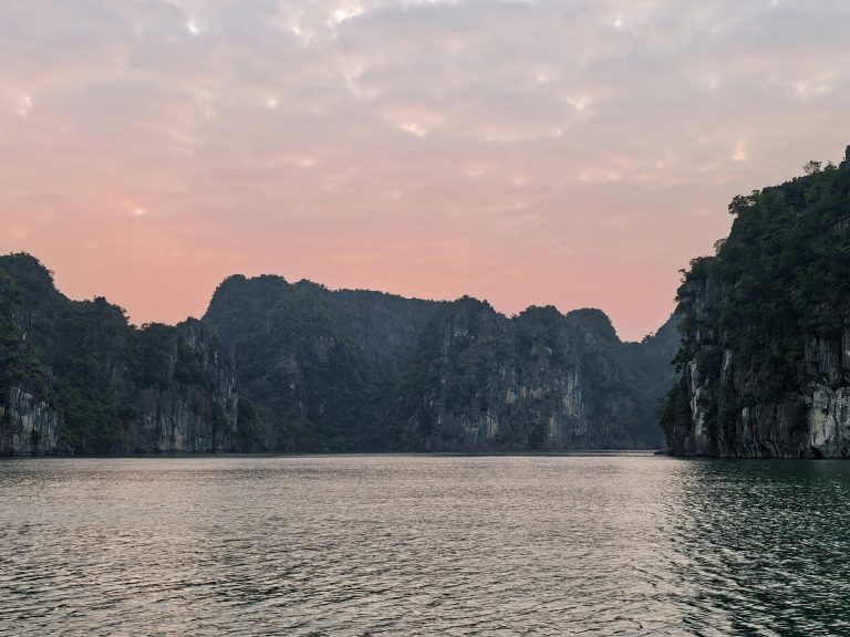 Beautiful view of Halong Bay's limestone formations with a pink sunset sky.