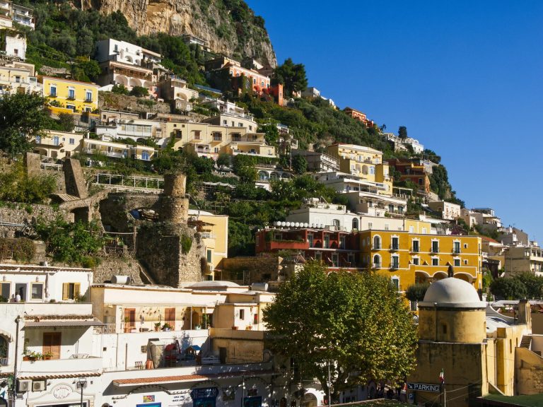 Colorful hillside buildings in Positano, Italy under a clear blue sky.
