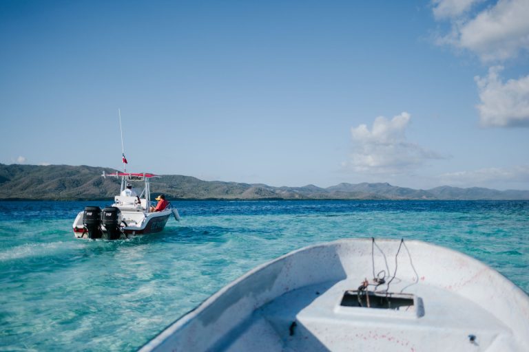 Boats sailing over rippling turquoise seawater surrounded by hills under blue sky in sunny summer day