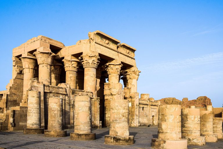 Explore the stunning ancient Egyptian temple ruins featuring iconic columns under a clear blue sky.