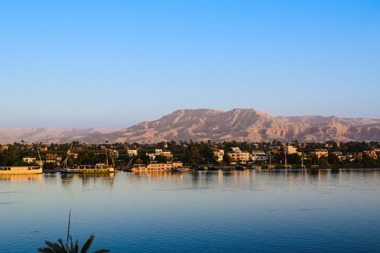 Captivating view of the Nile River with lush greenery and distant desert mountains in Egypt.