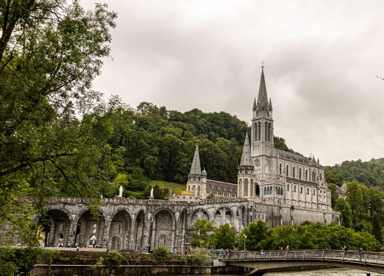 Stunning view of the Basilica of Our Lady of Lourdes against lush green landscape.