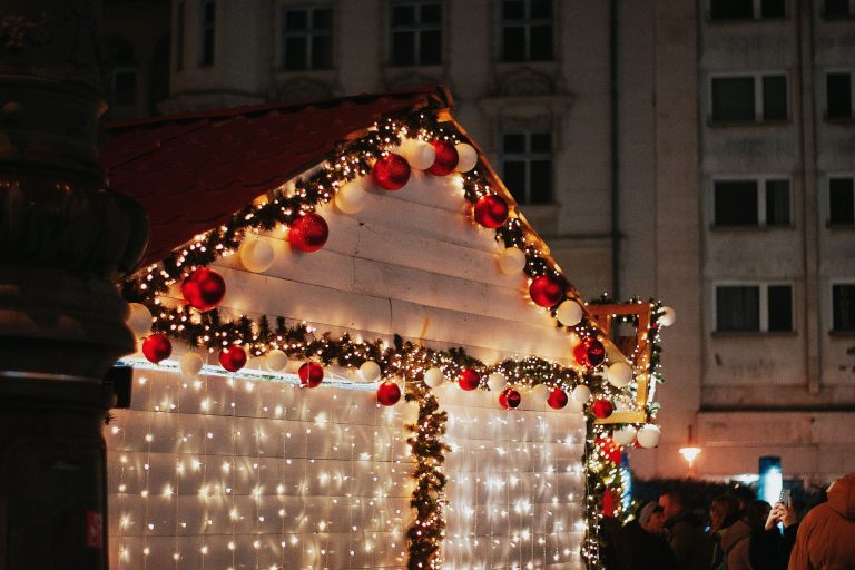 A charming Christmas market stall decorated with lights and ornaments in Budapest at night.