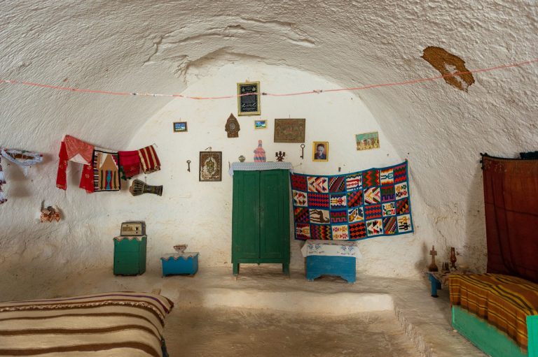 Explore a unique Tunisian cave interior with vibrant decor and traditional furnishings.