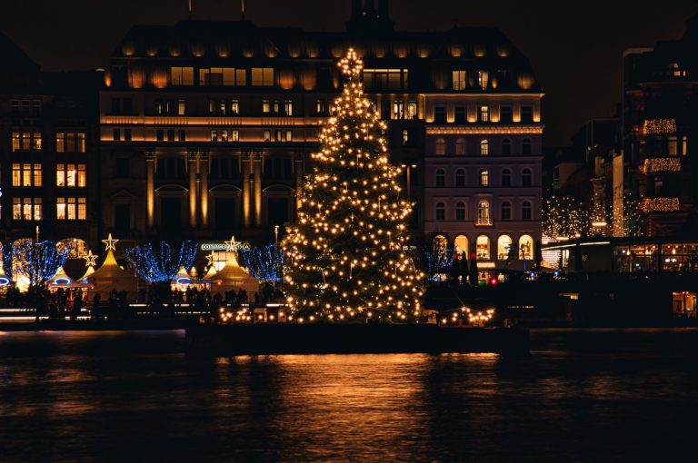 A beautifully lit Christmas tree against a cityscape backdrop at night, capturing holiday spirit.