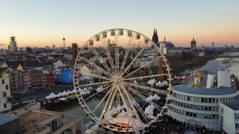 Captivating aerial view of Cologne cityscape featuring a Ferris wheel at sunset.