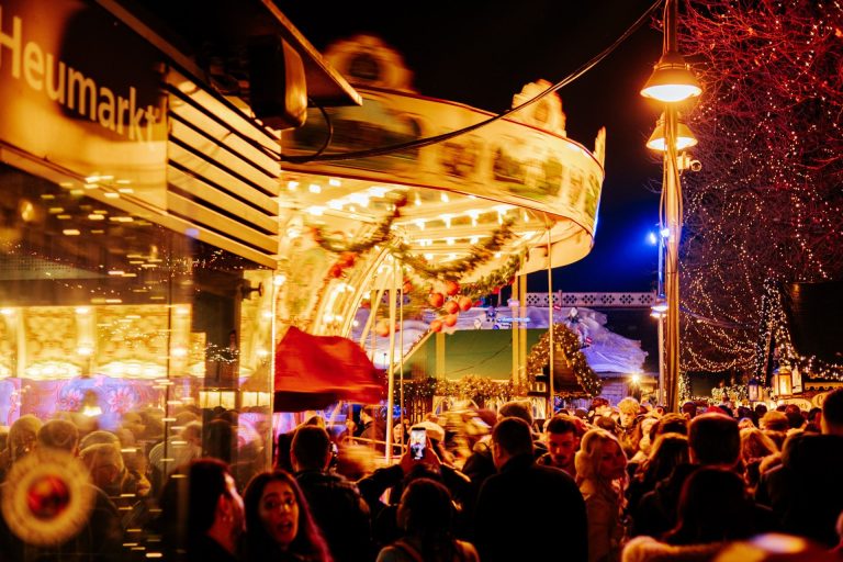 A lively scene at Cologne's Christmas market with a carousel ride and festive lights, captivating crowds in winter.