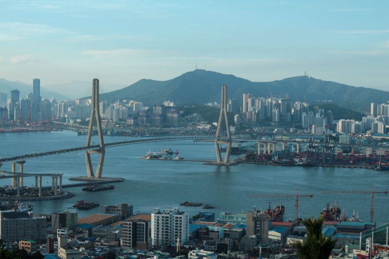 Scenic view of Busan's urban landscape with a prominent bridge and harbor.