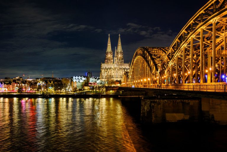 A breathtaking night view of Cologne Cathedral and Hohenzollern Bridge over the Rhine River in Germany.