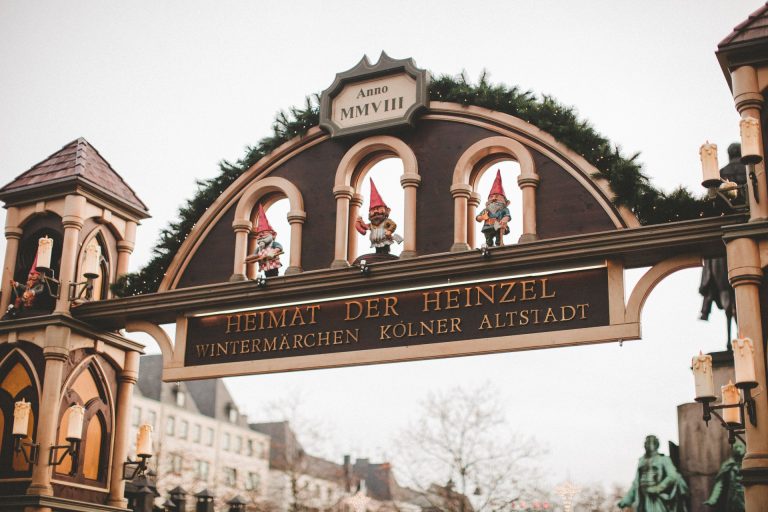 Charming Christmas market entrance with festive decorations and elf sculptures in Cologne, Germany.