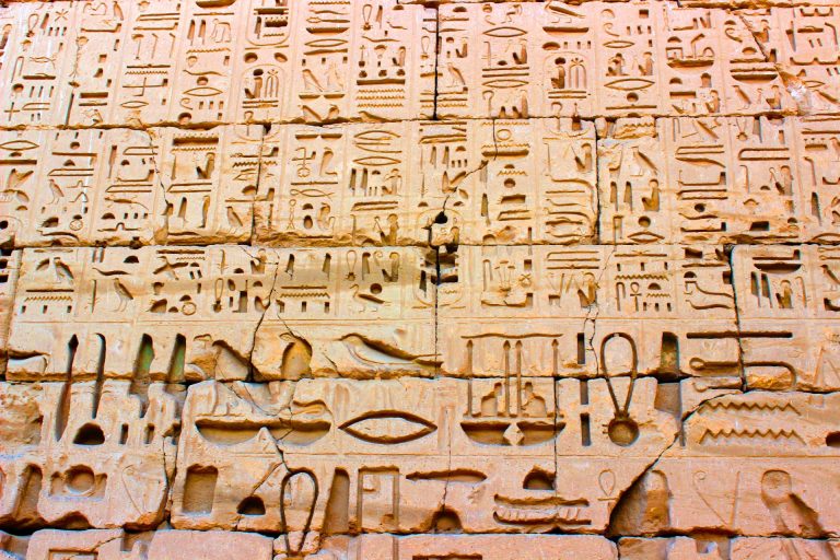 Detailed carvings of ancient Egyptian hieroglyphs on stone walls at Edfu Temple.