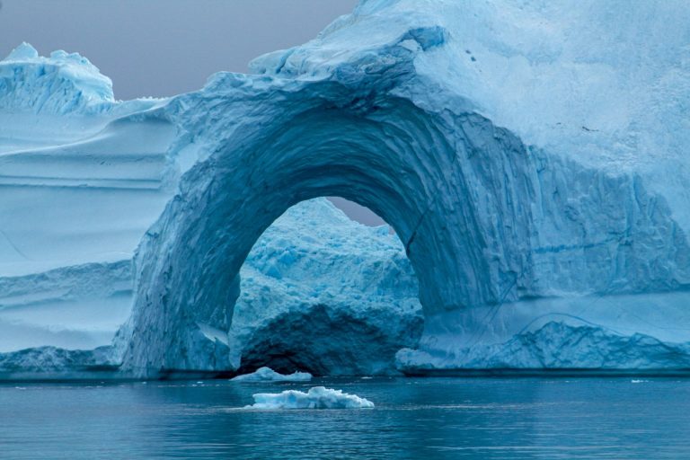A stunning view of a natural ice arch on a calm polar sea, showcasing icy beauty.