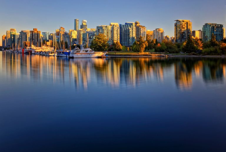 Beautiful reflection of Vancouver skyline with yachts at sunset, highlighting urban architecture.