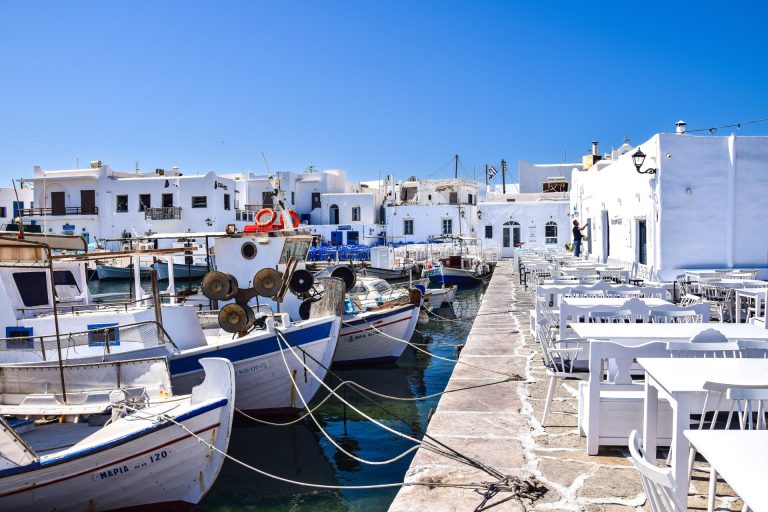 Charming coastal scene with boats and traditional Greek architecture in Paros harbor.
