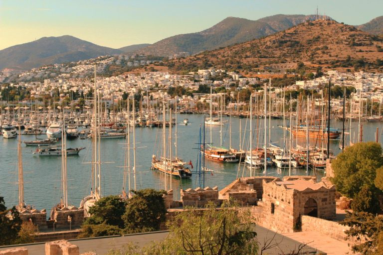 Breathtaking view of Bodrum harbor full of yachts, against picturesque hills and cityscape.