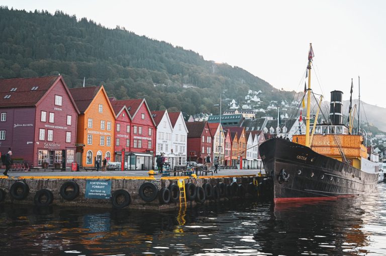 Scenic view of Bryggen wharf with colorful wooden buildings and docked ship in Bergen, Norway.