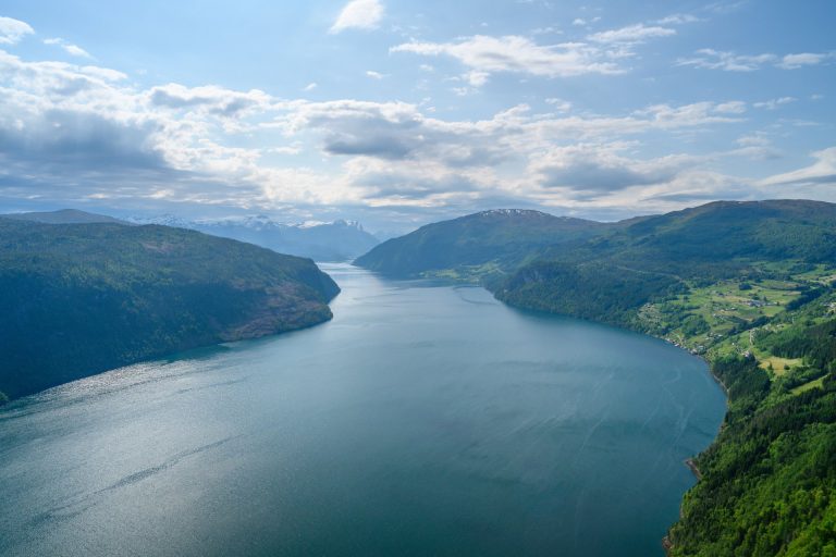 A stunning aerial view of a tranquil mountain lake surrounded by lush greenery and mountains.