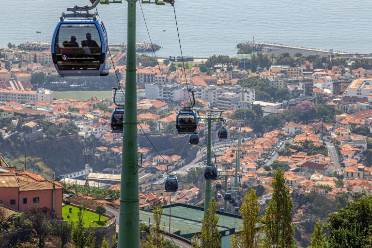 A scenic view of cable cars over Funchal, Madeira, with the ocean in the background.