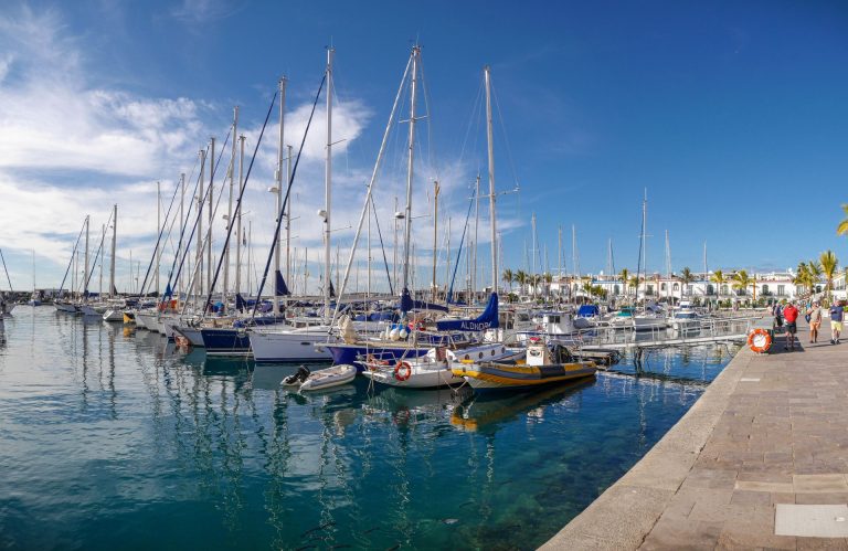 A beautiful marina with docked sailboats under a clear blue sky, captured in Gran Canaria.